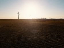An aerial view of wind turbines in a farm field taken with a drone.